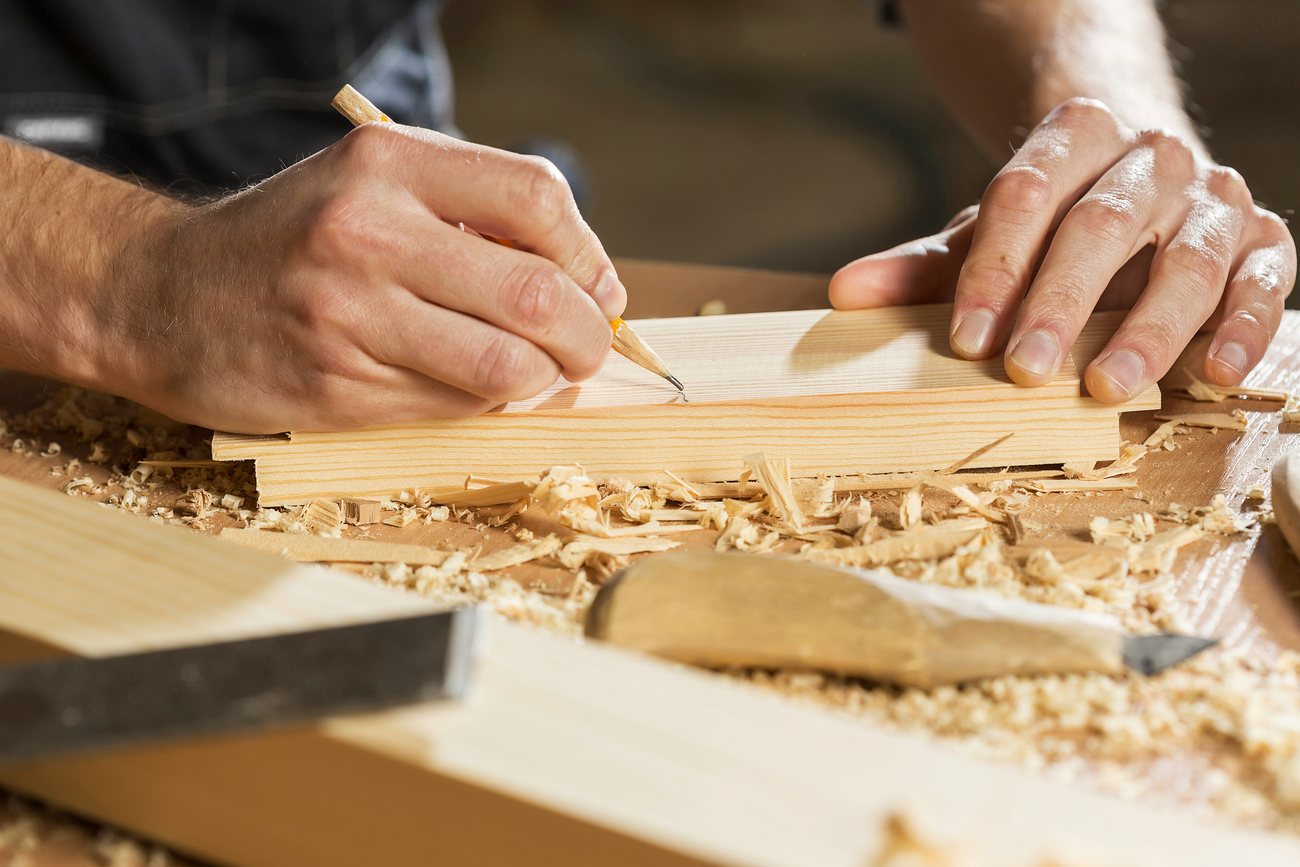 Carlos marcando y midiendo una tabla de madera en el taller